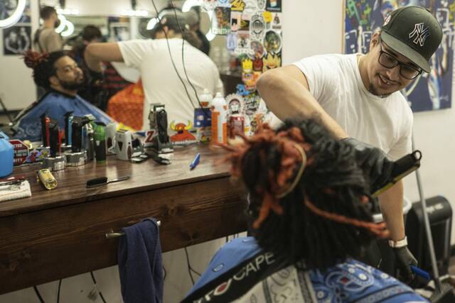 Barber Joe Ayala smiles and chats while trimming a beard for a customer. August 22, 2024, at Willy T's Barber Shop in Tarentum.